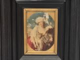 an old picture of a woman with a dog in a black frame
