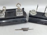 three silver objects on a table with a pen and a pencil