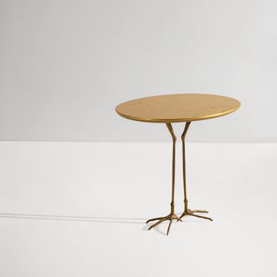 an image of a gold table with two legs and a round top