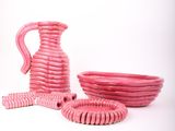 un vase, un bol et une assiette roses sur fond blanc