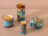 three vases and a cup sitting on a table