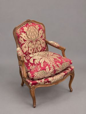 une chaise rouge et dorée dont l'assise est recouverte d'un tissu à motifs floraux