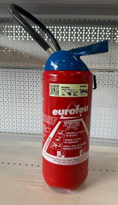 un extincteur rouge posé sur une étagère dans un magasin