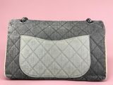 a grey and white purse sitting on top of a pink surface