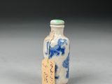 a small blue and white bottle with a tag on it