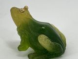 a green and yellow frog figurine sitting on a white surface