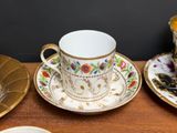 a cup and saucer sitting on a table next to a plate