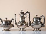 three silver teapots sitting on a white table