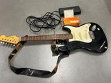 une guitare posée sur une table à côté d'une sangle de guitare