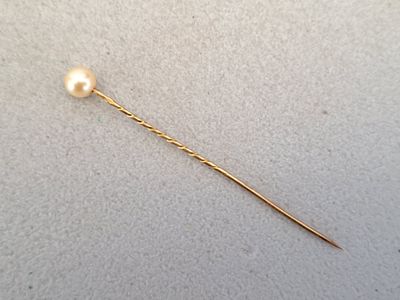 a close up of a gold pin with a pearl on it
