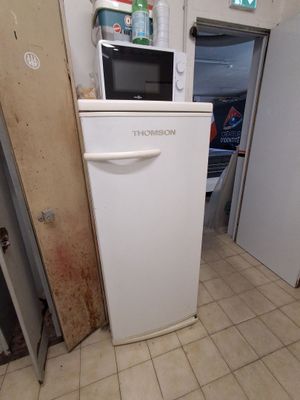 a white refrigerator and a microwave in a small room