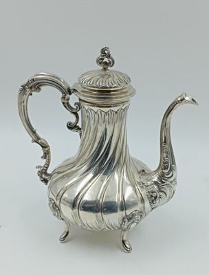 une théière ancienne en argent avec une anse, sur fond blanc