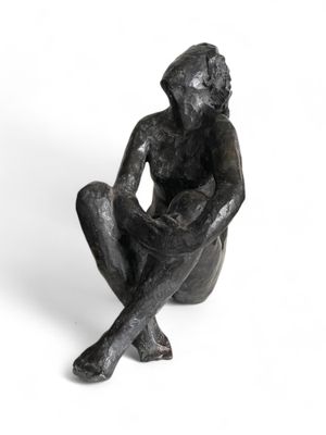 statue d'un homme assis à genoux sur un fond blanc