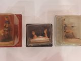 trois figurines miniatures représentant une femme allongée sur un lit, dans une boîte