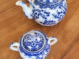 two blue and white teapots sitting on a wooden table