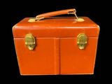 une valise orange posée sur une surface noire