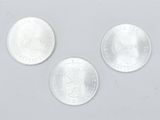 three silver coins are shown on a white surface