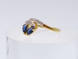 a close up of a diamond and sapphire ring on a clear surface