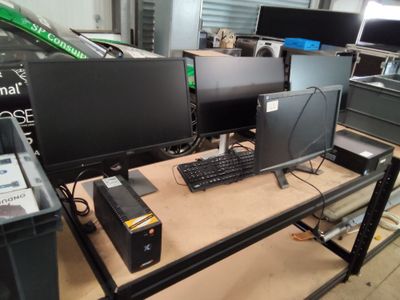 deux écrans et un clavier posés sur un bureau dans un garage
