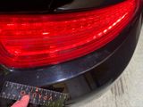 a person holding a ruler in front of a car ' s tail light