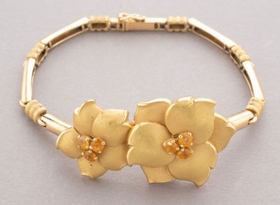 gold bracelet with flowers on it on a gray surface
