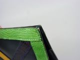 someone is holding a black and green purse with a green strap