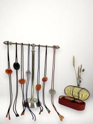 une série de colliers suspendus à un porte-colliers à côté d'un vase