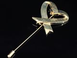 an image of a gold brooch with a ribbon and a bow