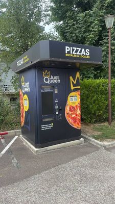 a pizza kiosk in the middle of a parking lot