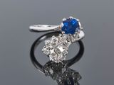 a close up of a sapphire and diamond ring on a reflective surface