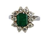 une image d'une bague avec une pierre verte entourée de diamants blancs