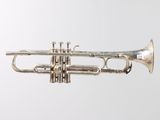 an old silver trumpet sitting on top of a white surface