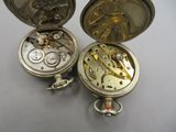 deux montres de poche en argent posées l'une à côté de l'autre sur une table