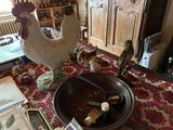 une statue de coq posée sur une table, à côté d'un bol de vin