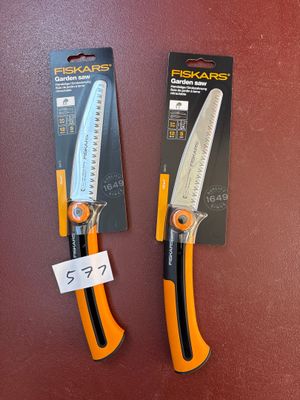 une paire de ciseaux orange et noirs posés sur une surface rouge
