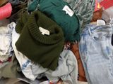 un tas de vêtements posé par terre à côté d'un autre tas de vêtements