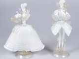 une paire de figurines en verre représentant une femme en robe blanche et un homme au chapeau blanc