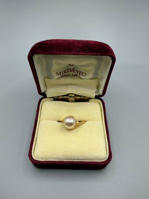 une photo d'une bague en or sertie d'une perle, dans un écrin en velours