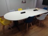 des chaises aux couleurs vives disposées autour d'une table blanche dans une salle de réunion
