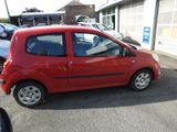 a small red car that is parked in a parking lot