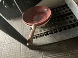 a red bowl sitting on the floor next to a metal grate