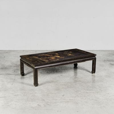 une table basse noire et dorée posée sur un sol en béton