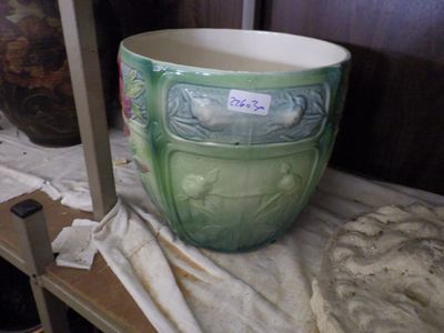 a large green vase sitting on a shelf next to other vases