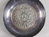 a silver plate with a coin on it on a table