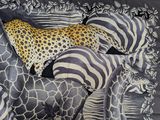 zebras, giraffes, and a cheetah laying on a bed