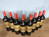six bottles of red wine lined up in a row on a wooden table