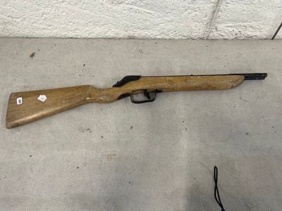 un fusil posé par terre près d'un mur