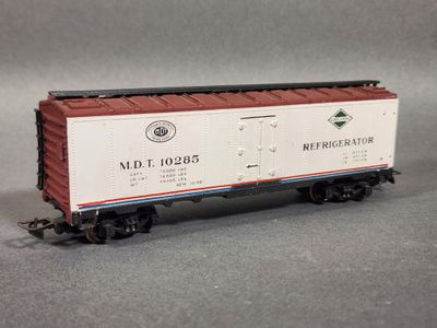 Le wagon du petit train est blanc et rouge, avec un toit rouge.