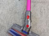 a pink corded vacuum that is on the ground