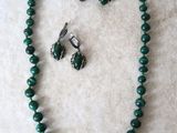 Ensemble collier et boucles d'oreilles orné de perles de verre vertes sur un fond en marbre